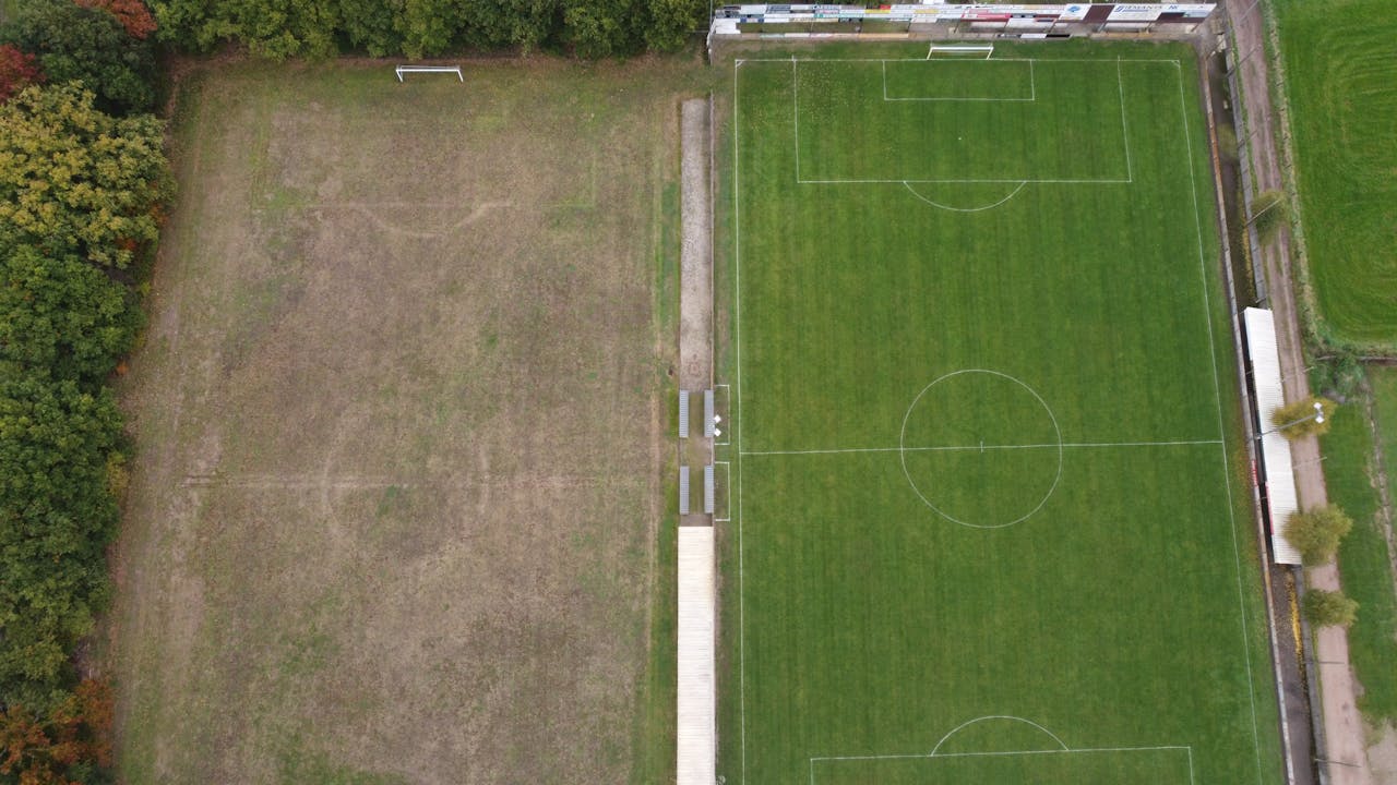 Aerial shot of two soccer fields in Arendonk, Belgium, showcasing lush green grass and clear lines.