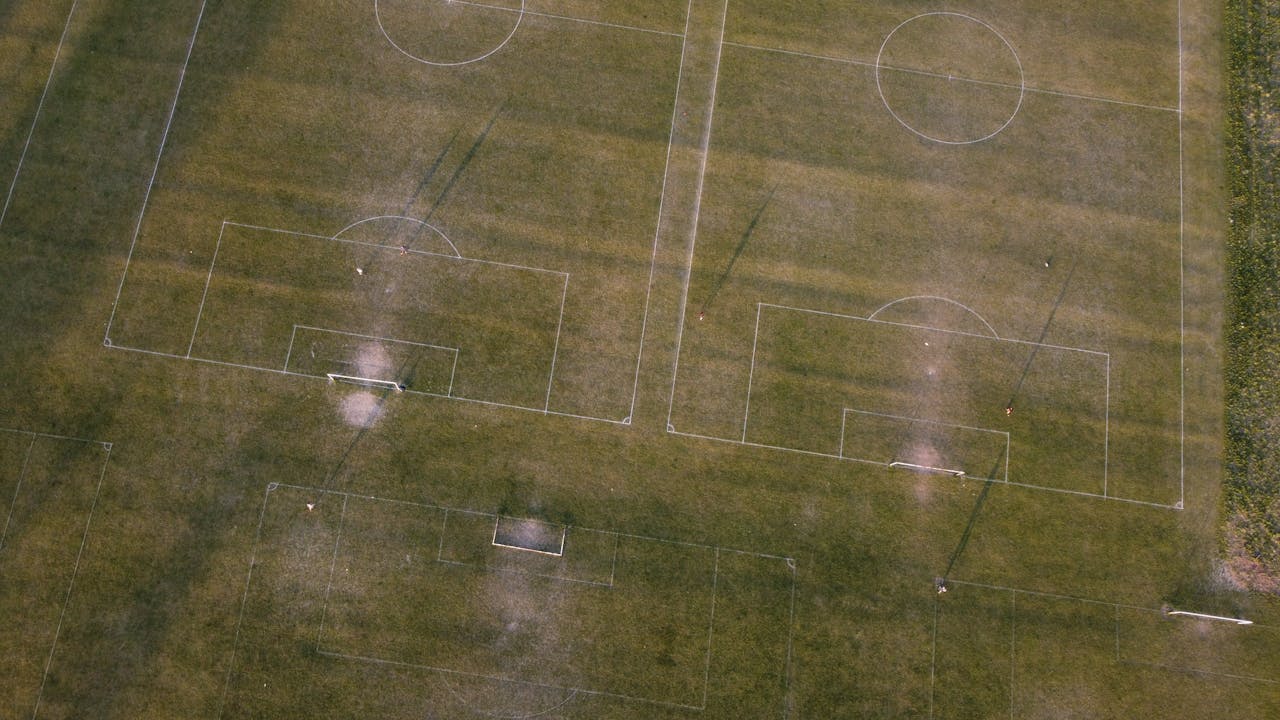 Aerial shot of soccer fields in Luton, England, showcasing green grass and goalposts.