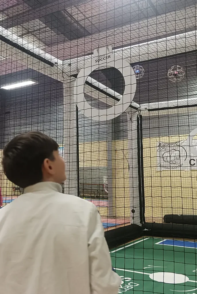 Adolescent pilotant un drone dans une arène de Drone Soccer